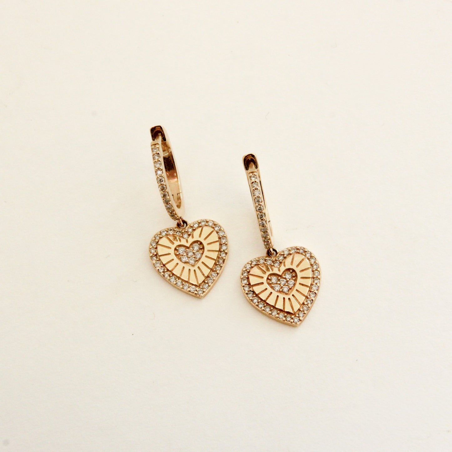 Heart-shaped gold earrings on a beige background