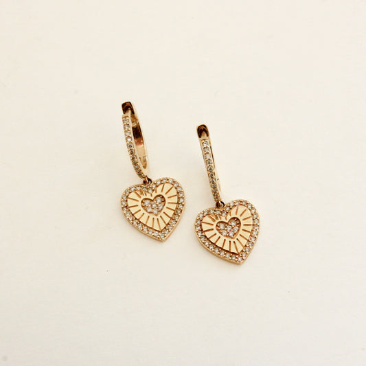 Heart-shaped gold earrings on a beige background
