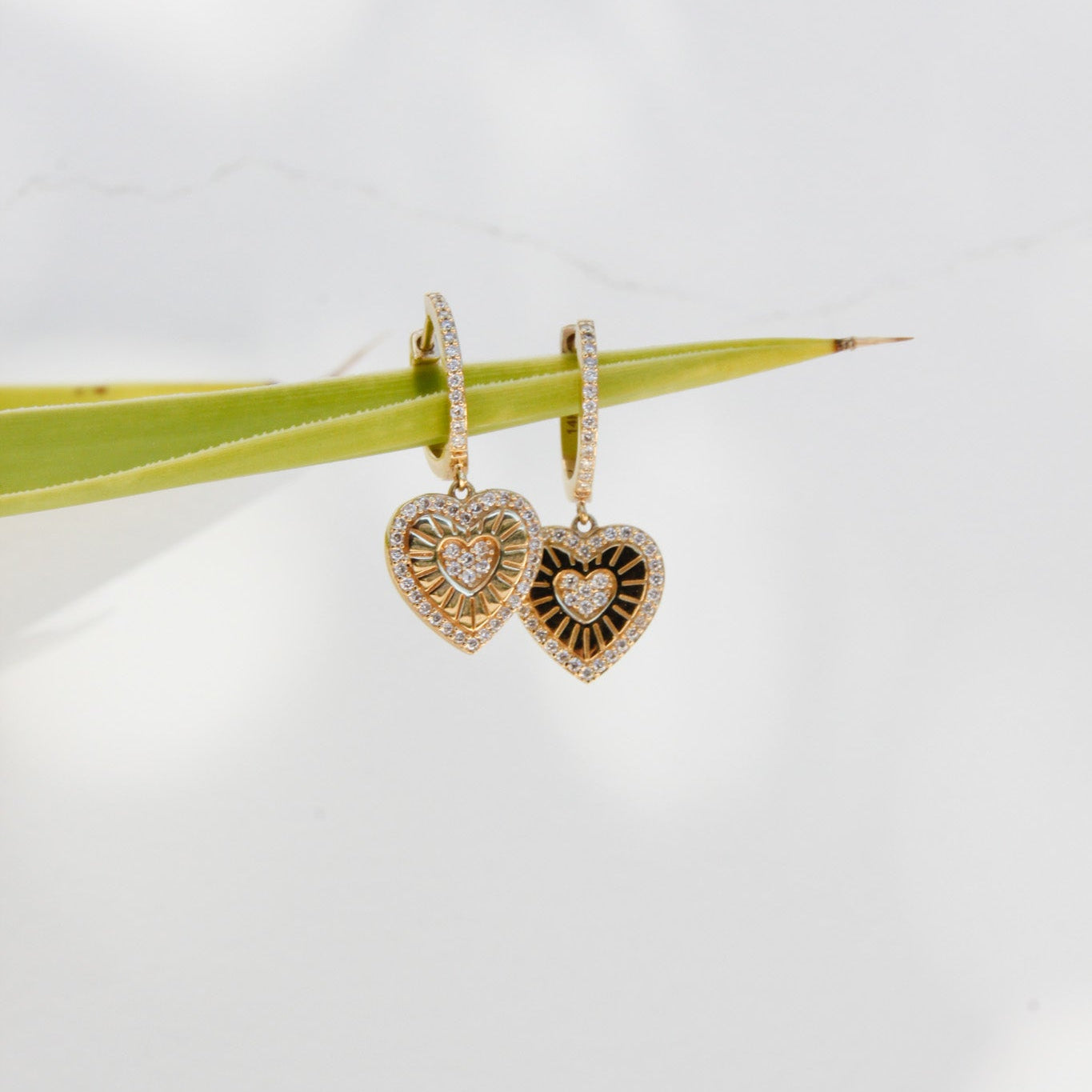 Heart-shaped earrings with gold and diamond details on a white background