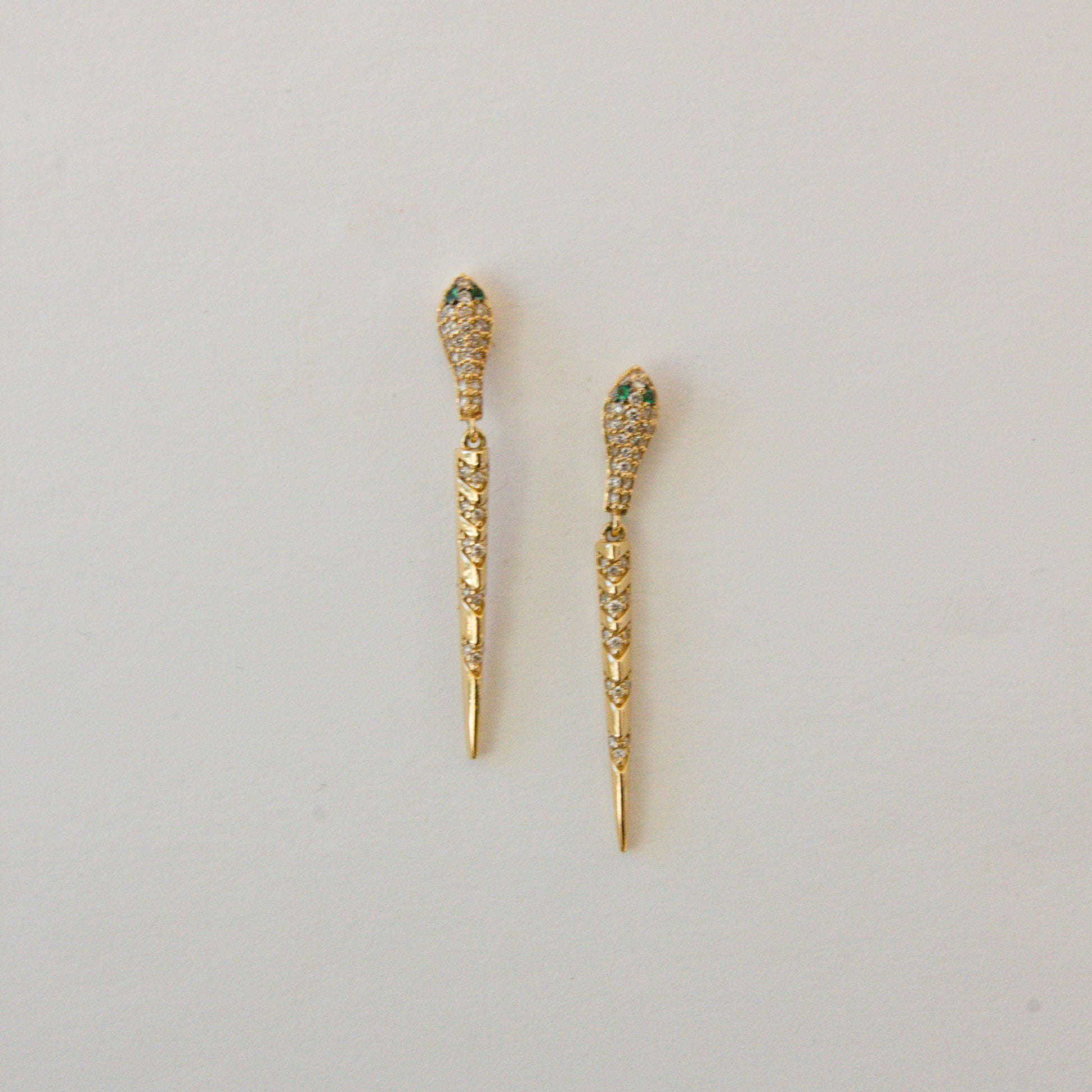 Gold earrings with gemstones on a light gray background