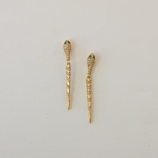 Gold earrings with gemstones on a light gray background