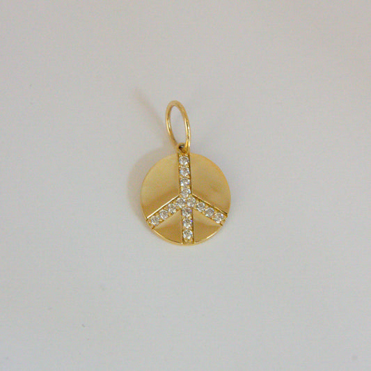 Gold peace sign pendant with clear stones on a light gray background