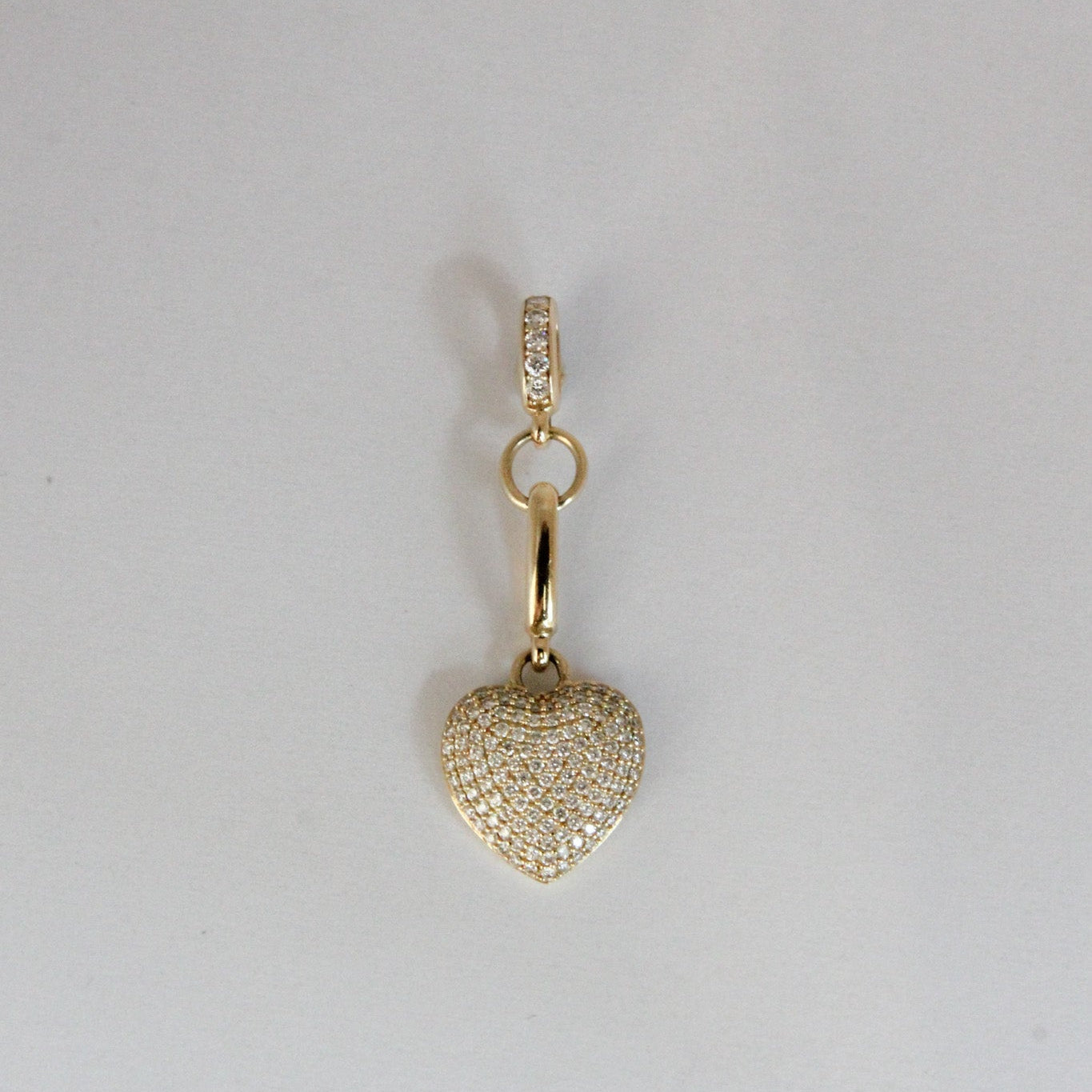 Gold heart-shaped pendant with a chain on a light gray background