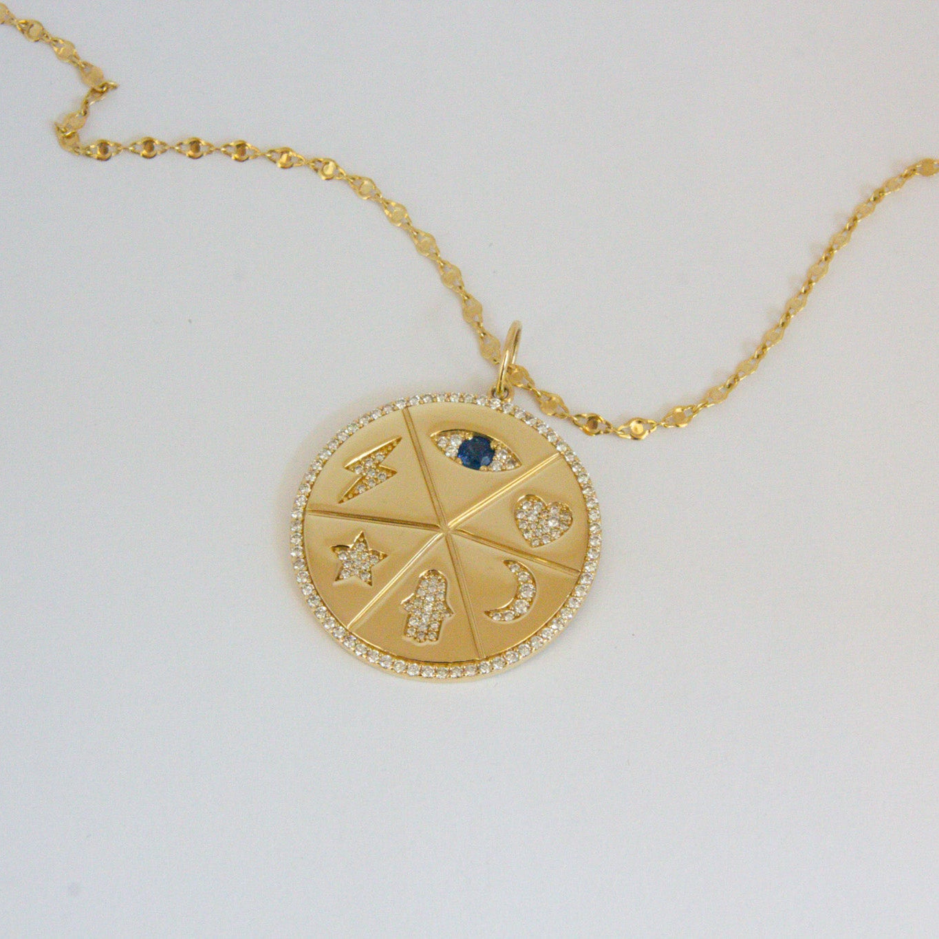Gold necklace with a circular pendant on a light gray background