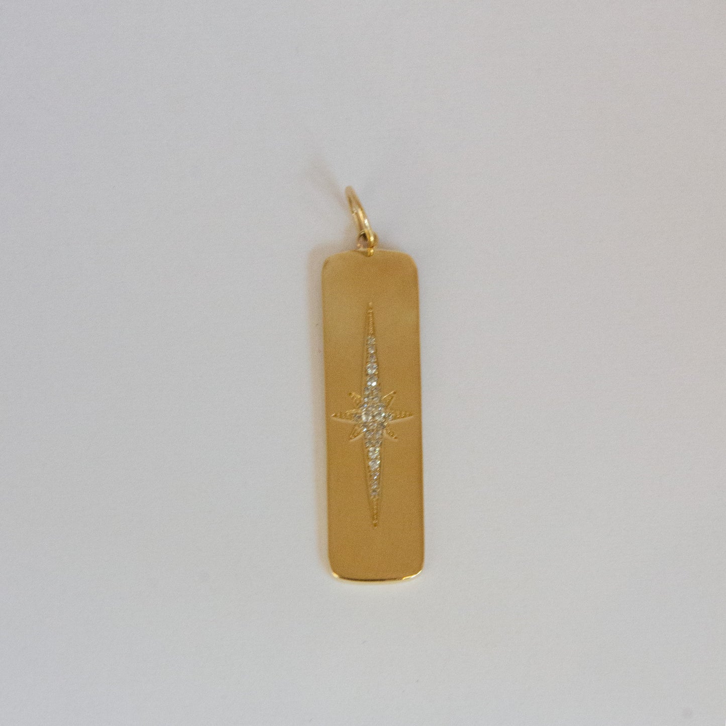 Gold pendant with star design on a light gray background