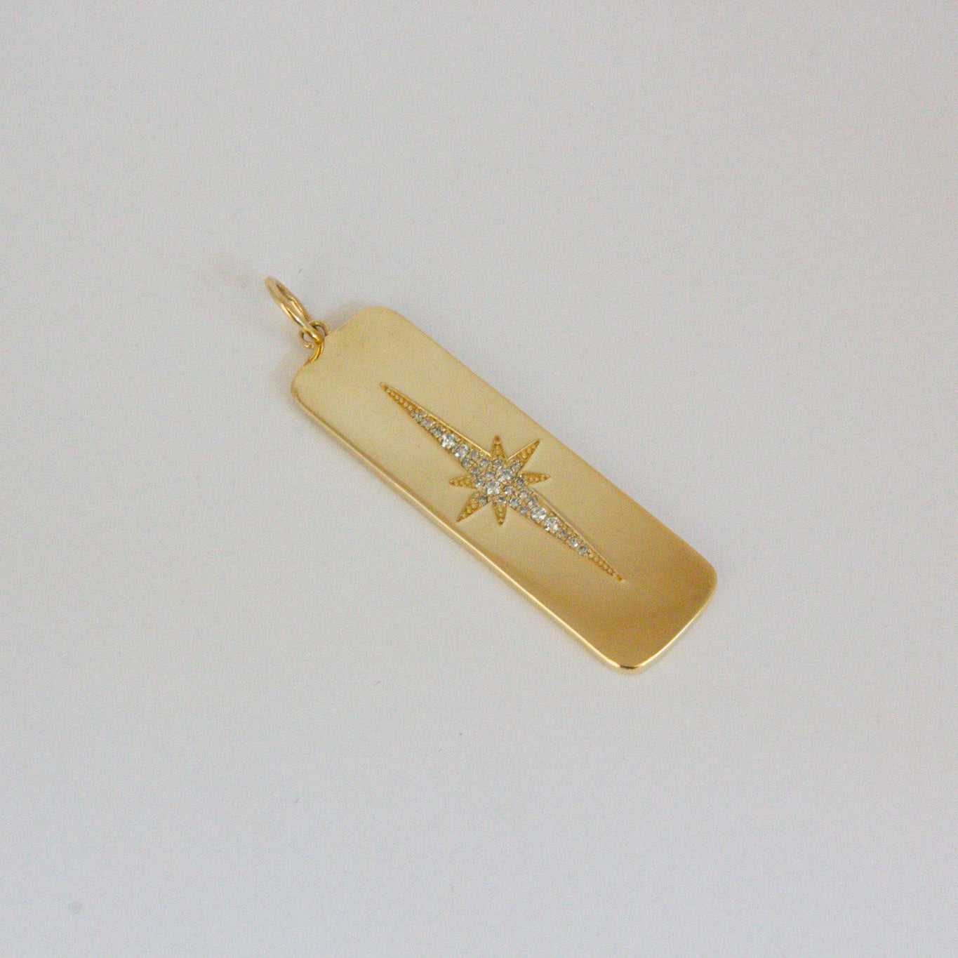 Gold pendant with star design on a light gray background