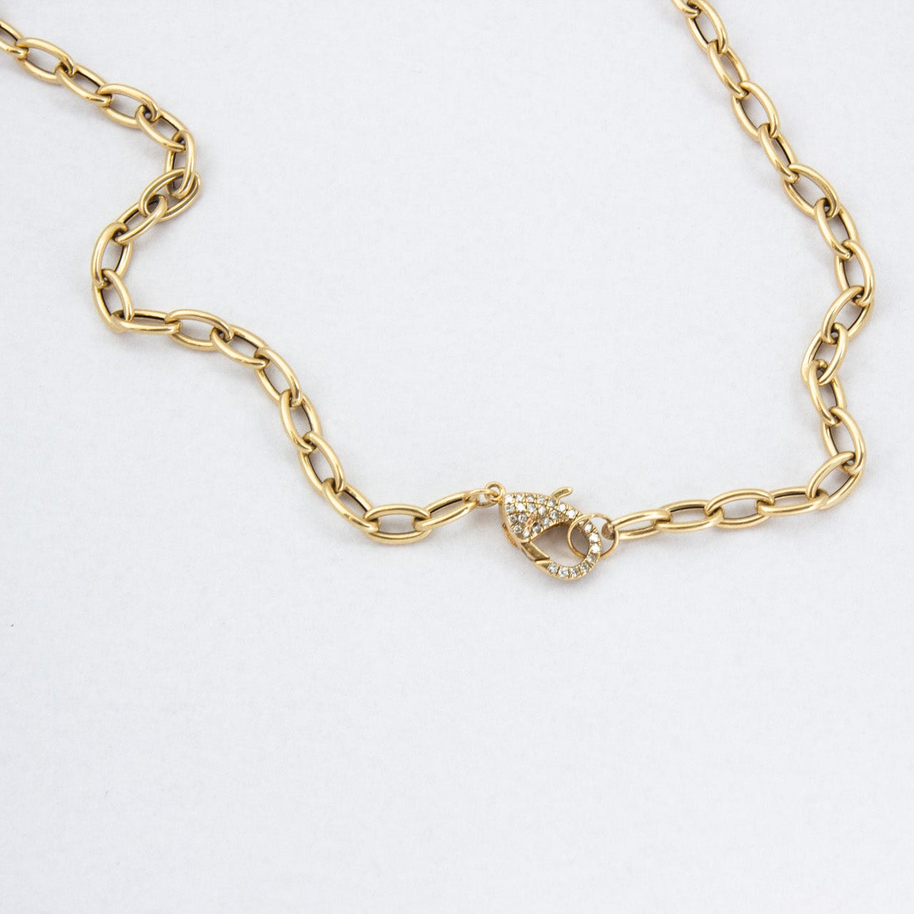 Gold chain bracelet with a heart clasp on a white background