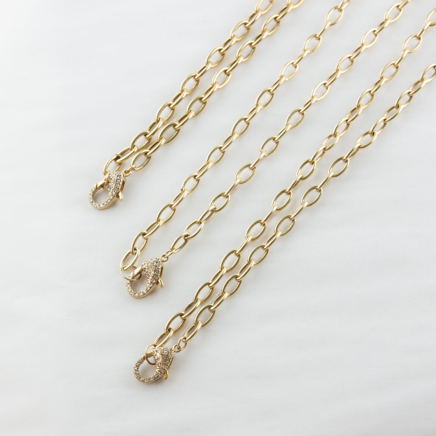Two gold chains with clasp on a light gray background