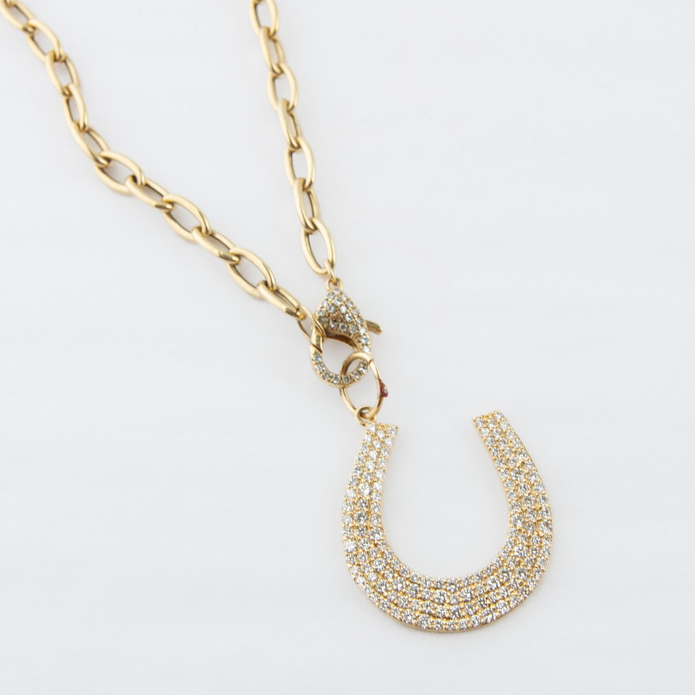 Gold necklace with a horseshoe-shaped pendant on a white background