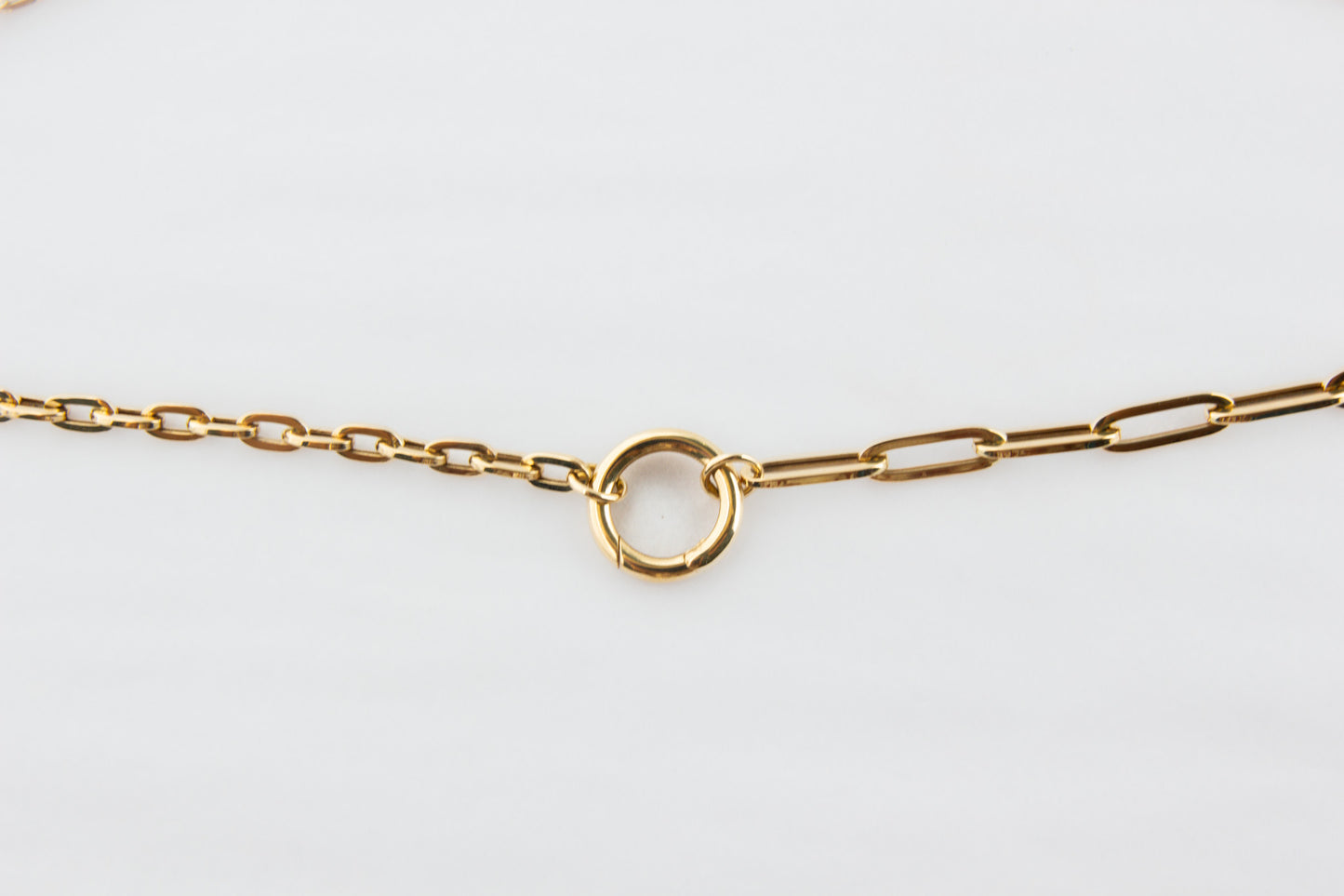 Gold chain bracelet on a light gray background