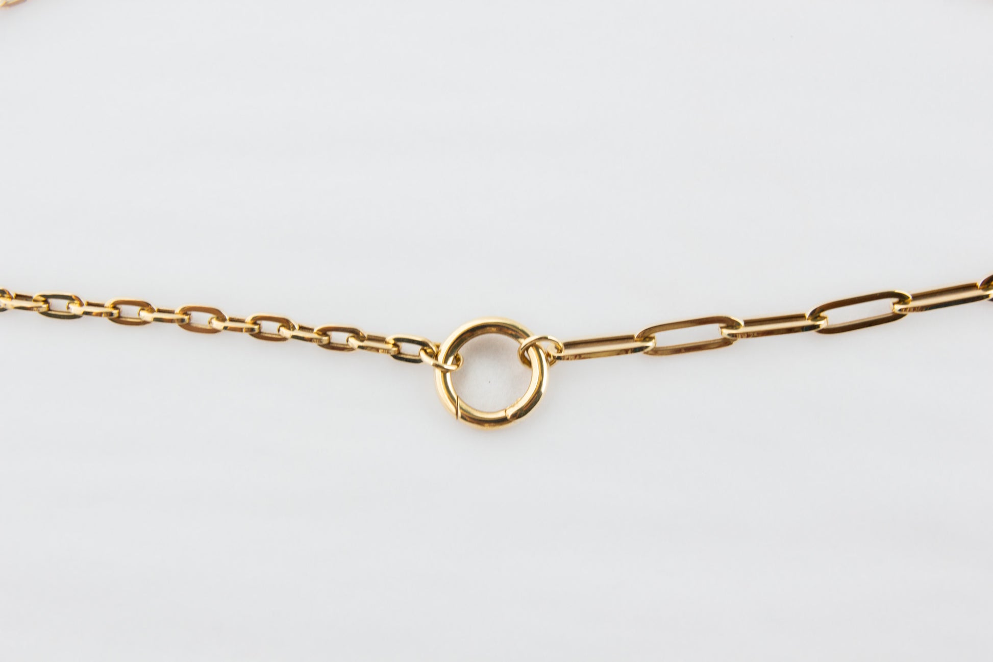 Gold chain bracelet on a light gray background