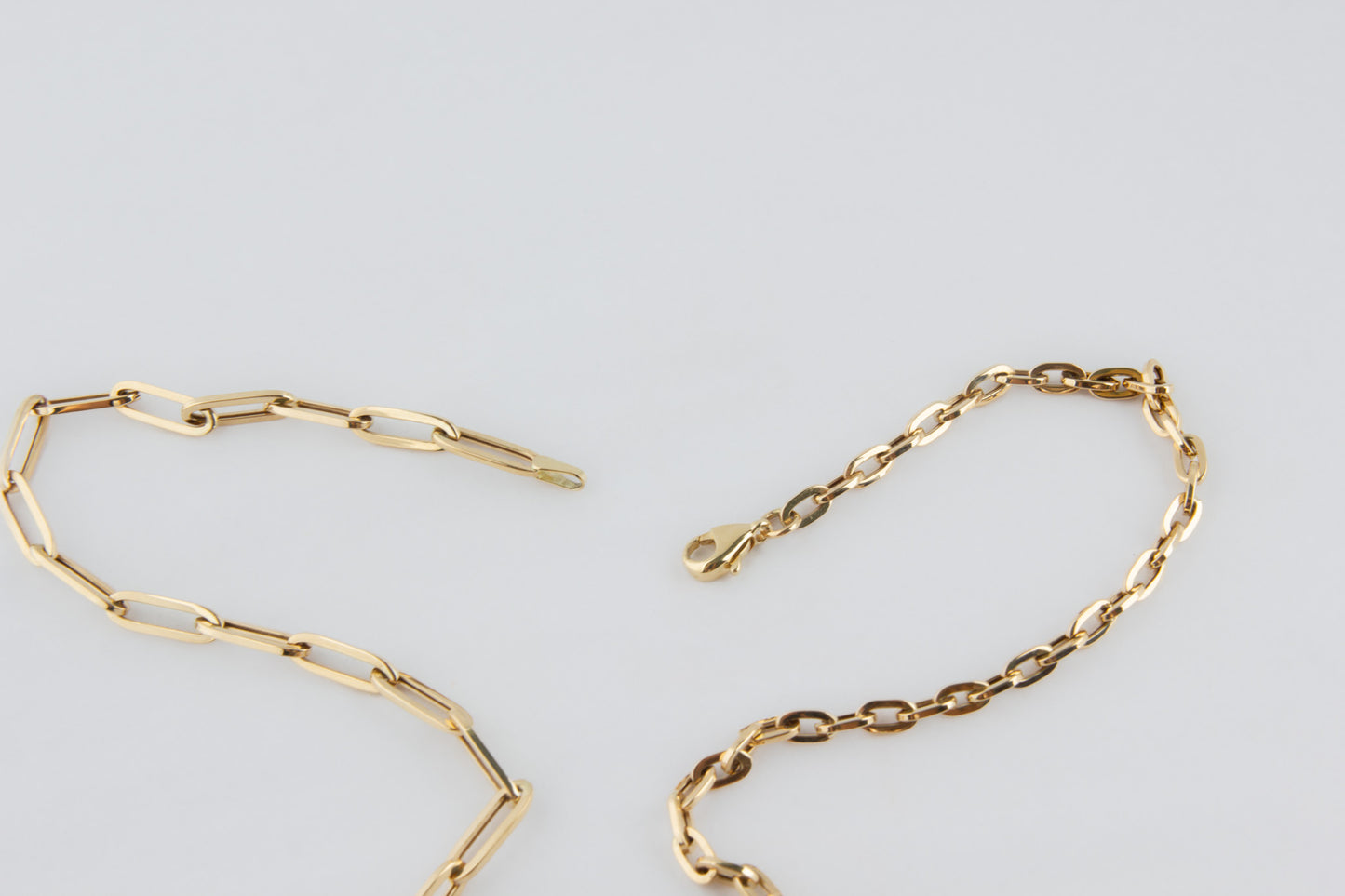 Gold chain bracelet on a light gray background