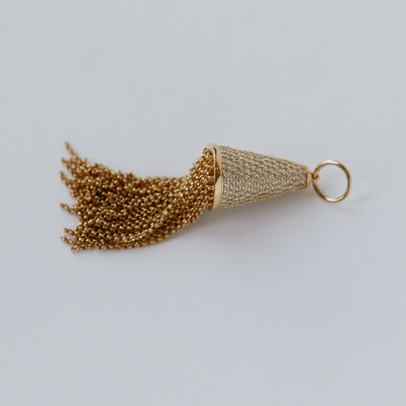 Gold tassel charm on a light gray background