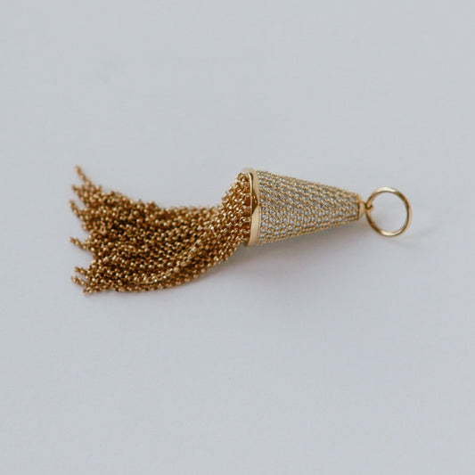 Gold tassel charm on a light gray background