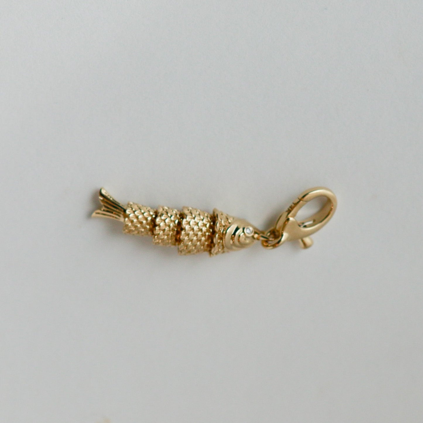 Gold fish-shaped charm on a gray background