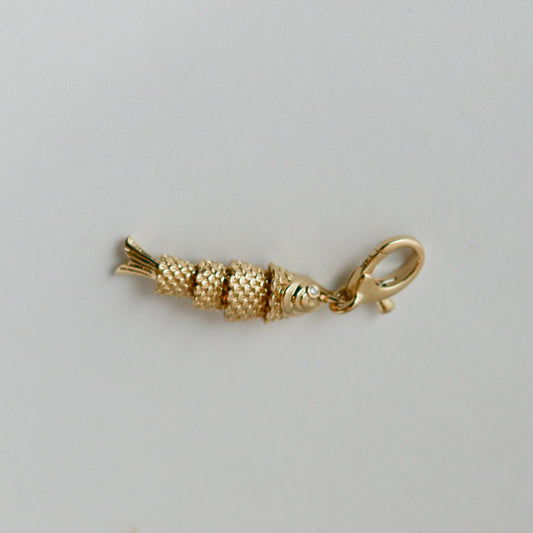 Gold fish-shaped charm on a gray background