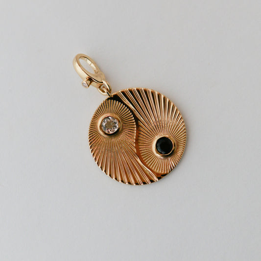 Gold pendant with intricate design on a gray background