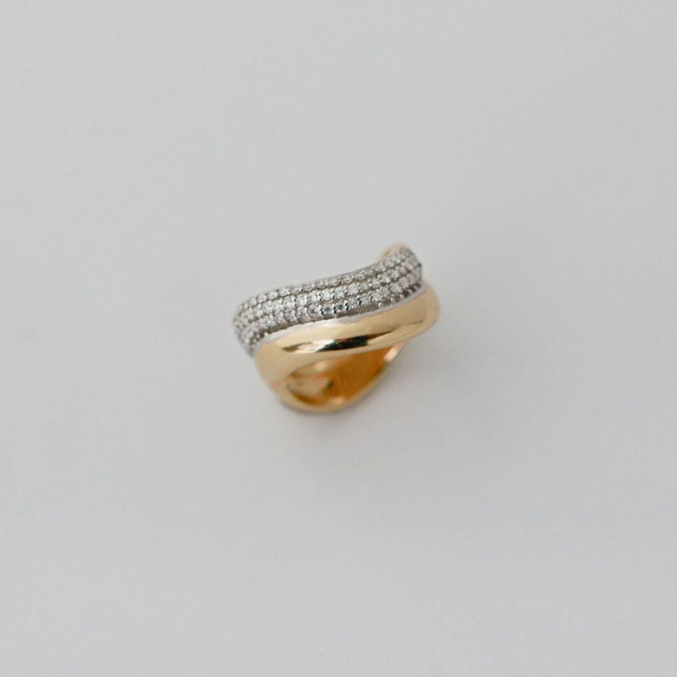Gold ring with diamond accents on a light gray background