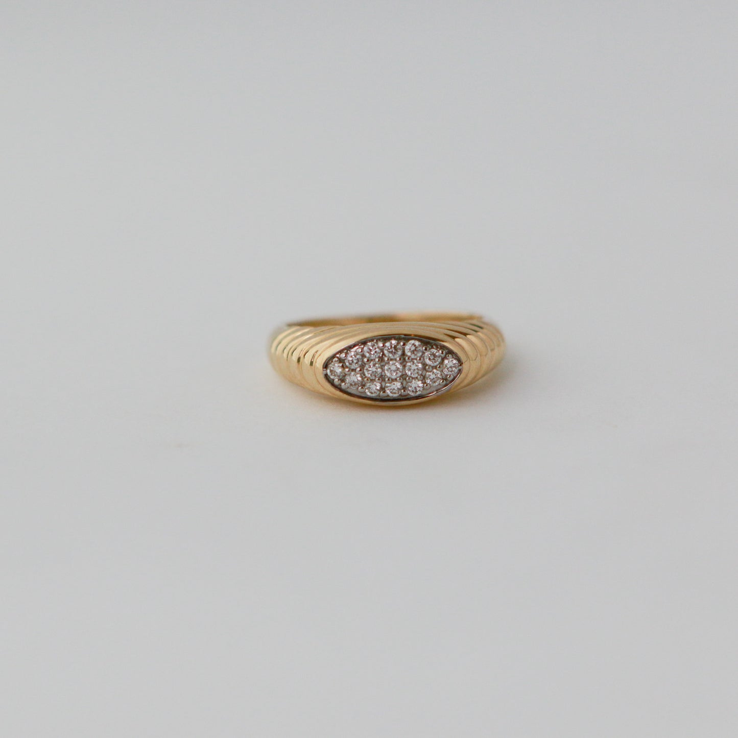 Gold ring with diamond pavé on a light gray background
