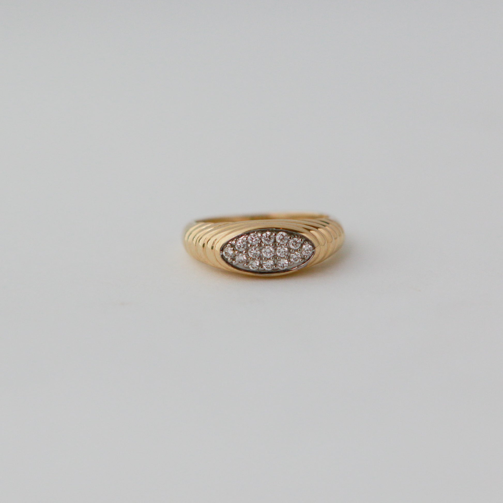 Gold ring with diamond pavé on a light gray background