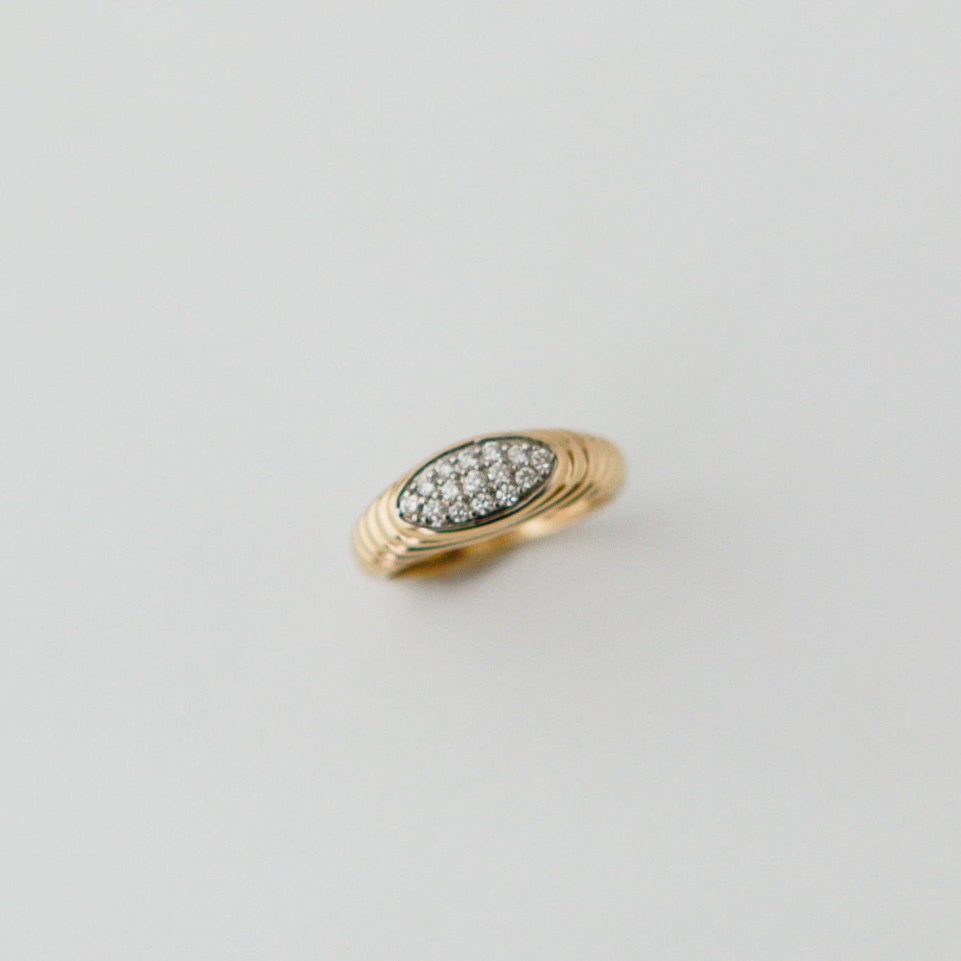 Gold ring with embedded stones on a light gray background