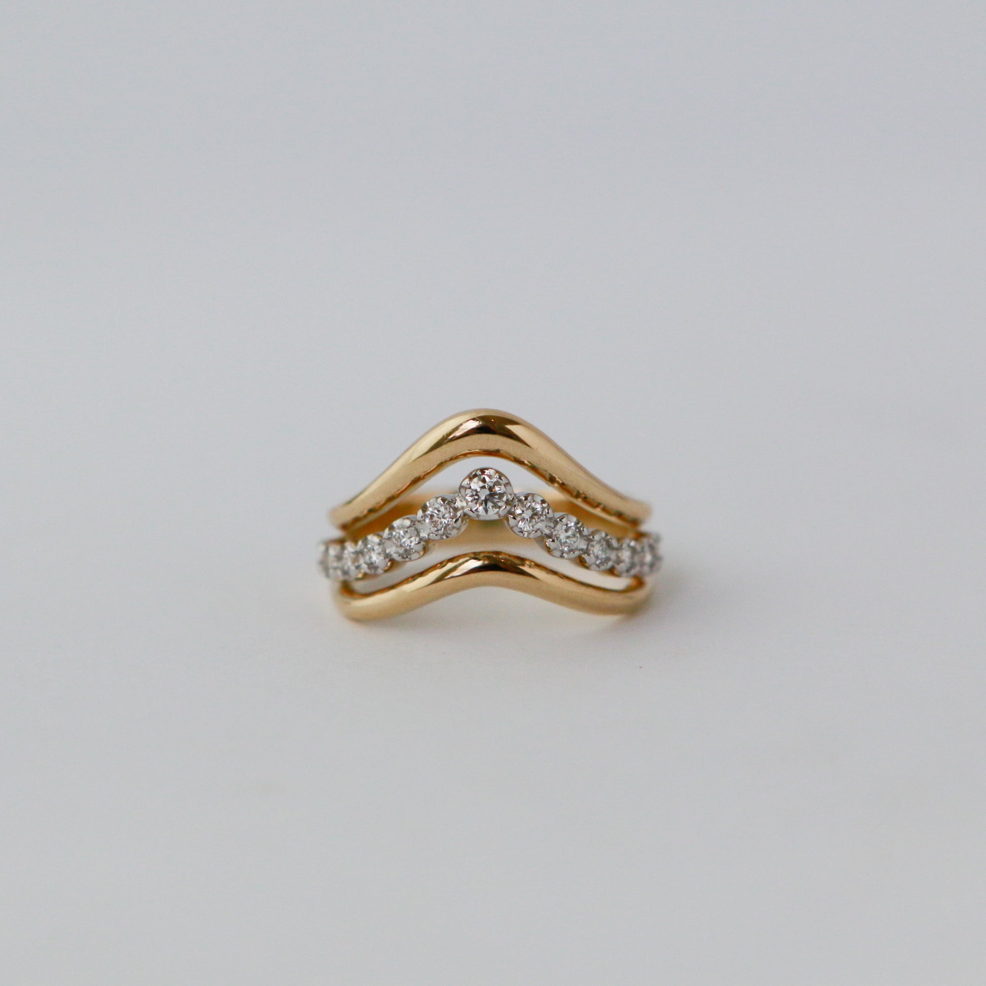 Gold ring with diamond accents on a light gray background