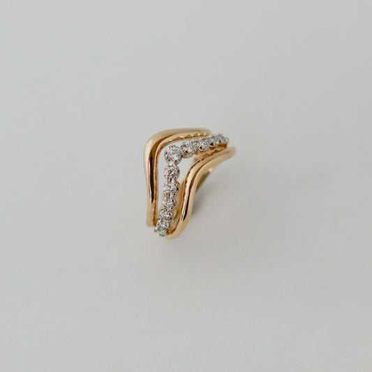 Gold earring with small diamonds on a light gray background