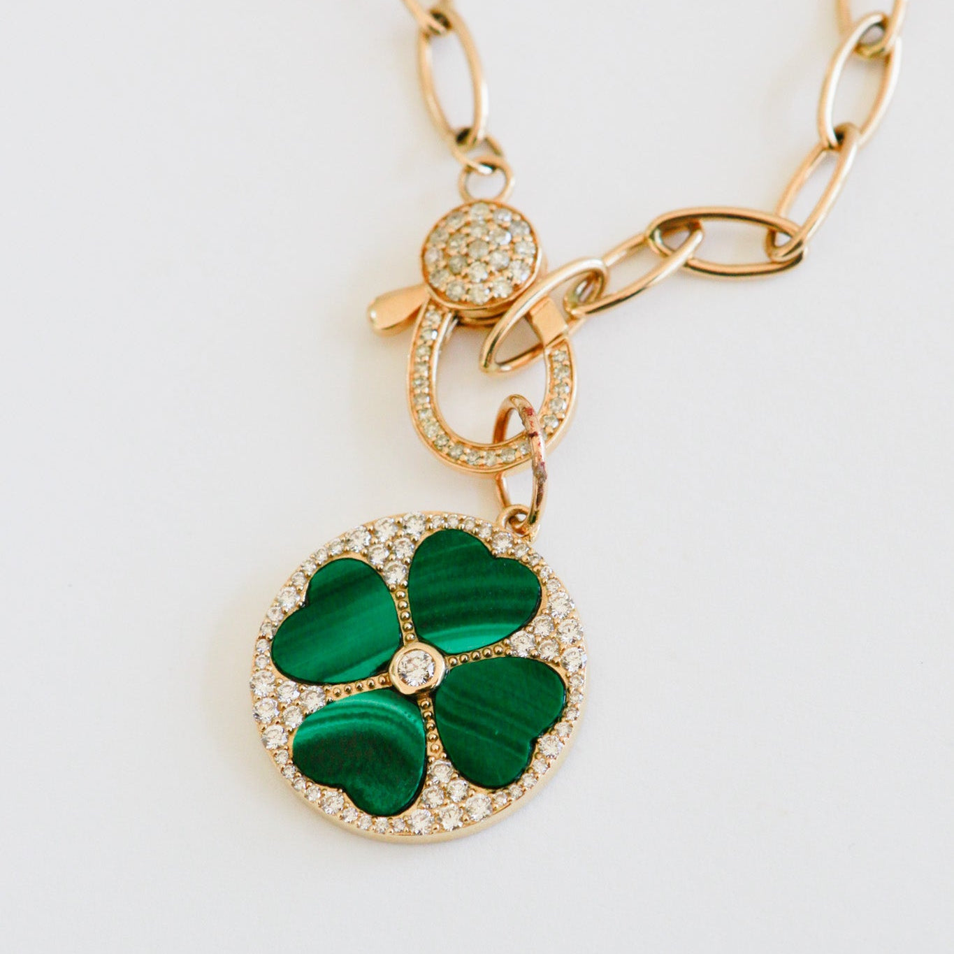 Gold necklace with a green clover pendant on a white background