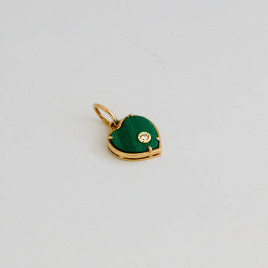 Gold pendant with a green heart-shaped stone on a light gray background