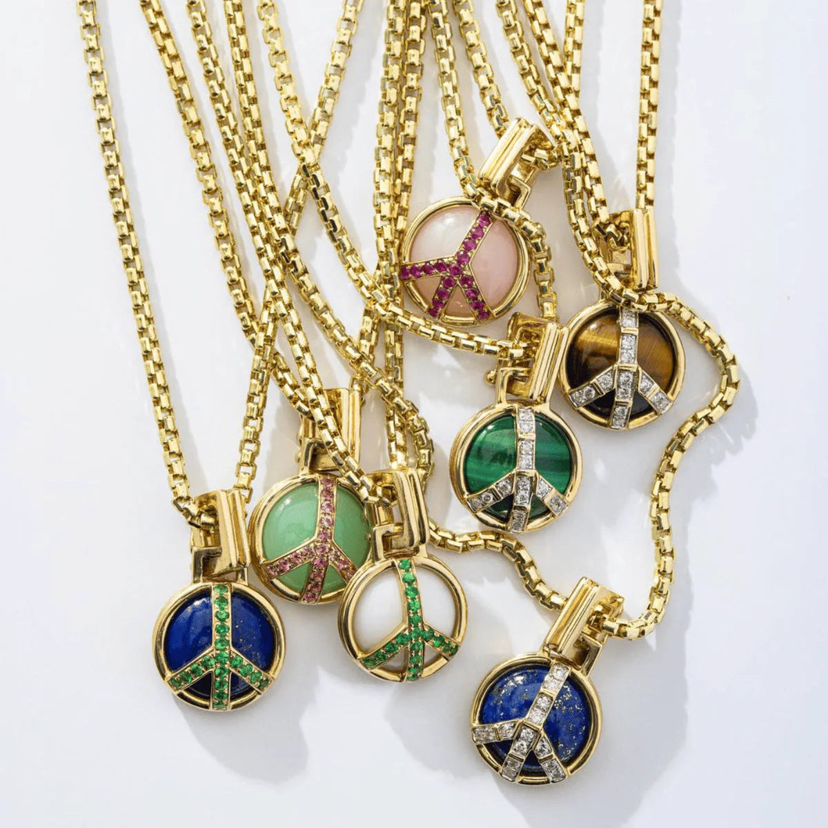 Gold necklaces with peace sign pendants on a white background
