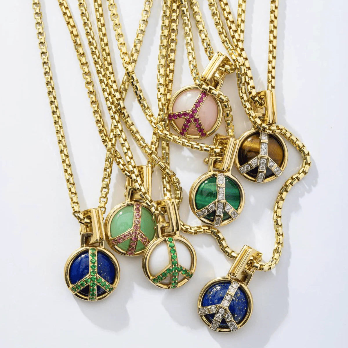 Gold necklaces with peace sign pendants on a white background