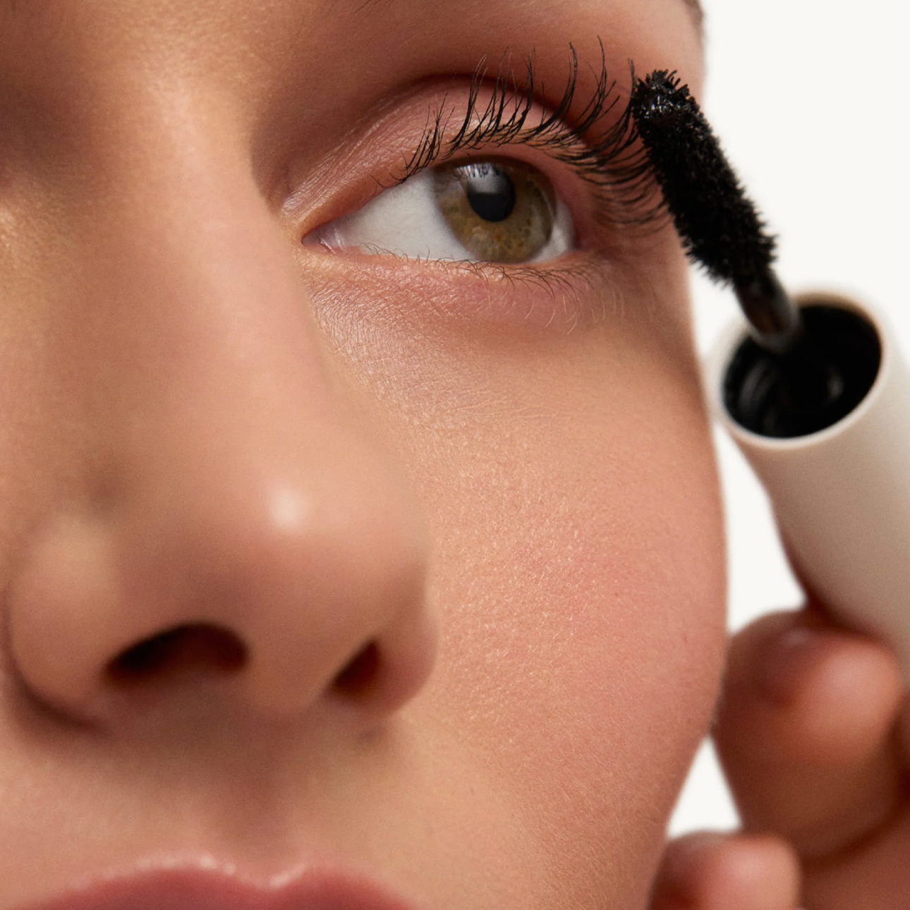 Person applying mascara to their eyelashes with a close-up focus on the eye area.