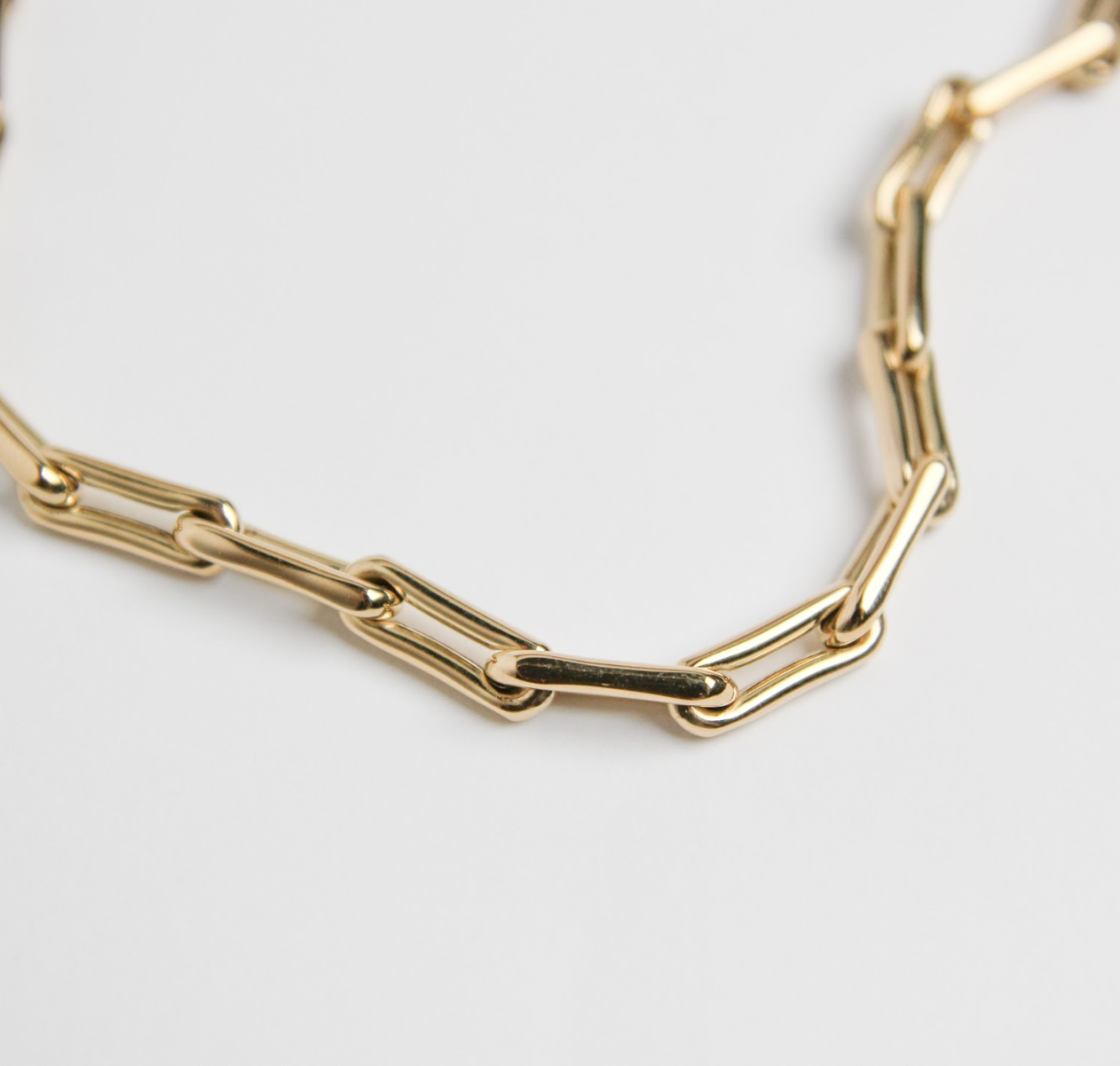 Gold chain bracelet on a light gray background