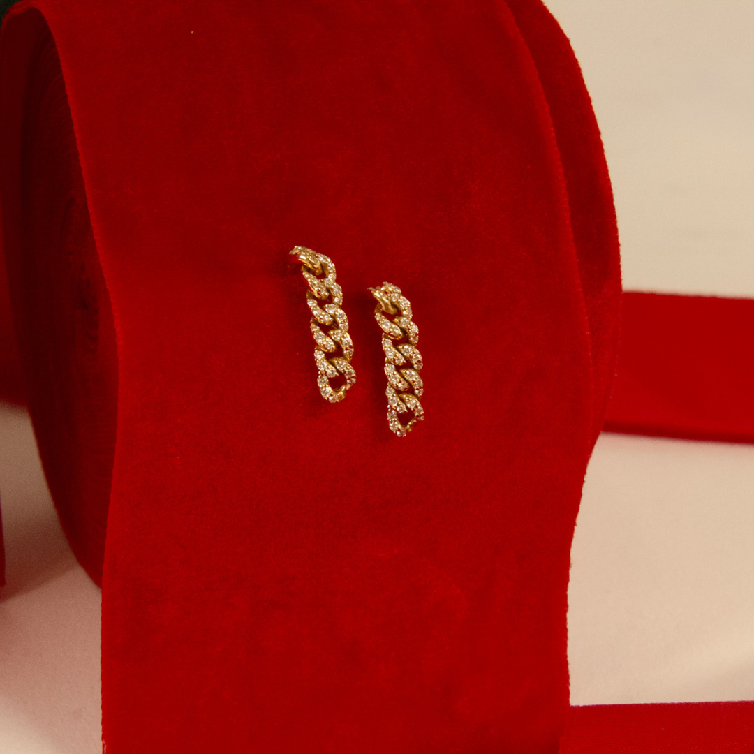 Gold chain earrings on a red fabric background